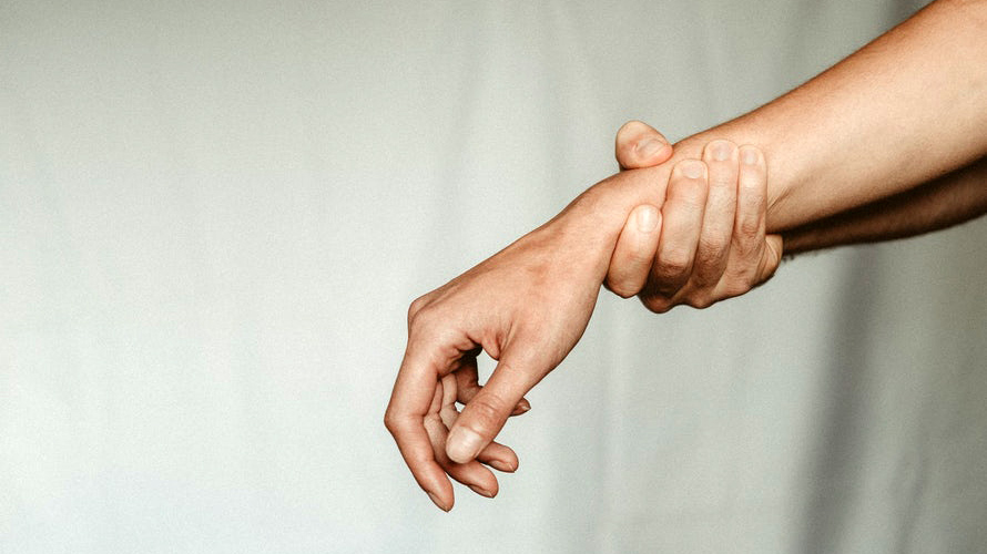 Hand holding arm at wrist, as though to alleviate pain