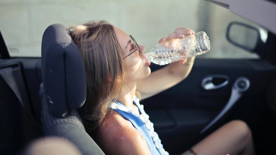 Woman in car on a hot day drinking water