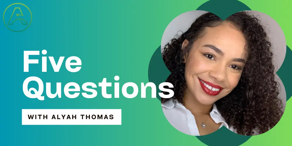 A green and blue graphic with white text that reads “Five Questions with Alyah Thomas” and a headshot of Alyah Thomas. In the photo, she is centered on a light gray background in a tightly cropped photo. Alyah is a mixed-race, Black-presenting young woman in her late twenties. She has a light-to-medium complexion, dark brown, back-length curly hair, and deep brown eyes. Her curls are pulled back on the side closest to the camera, with bangs cascading over the other, exposing a smiling face.