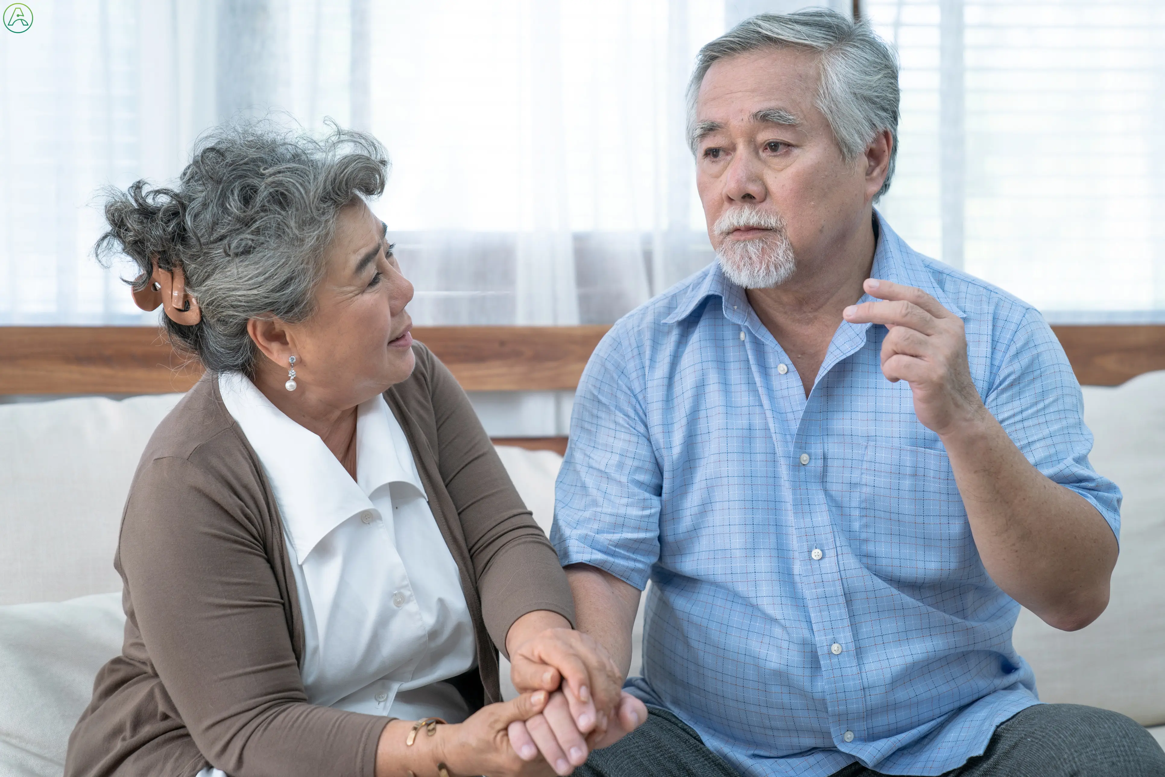 An elderly Asian couple sits in their living room, the husband struggles to remember something.