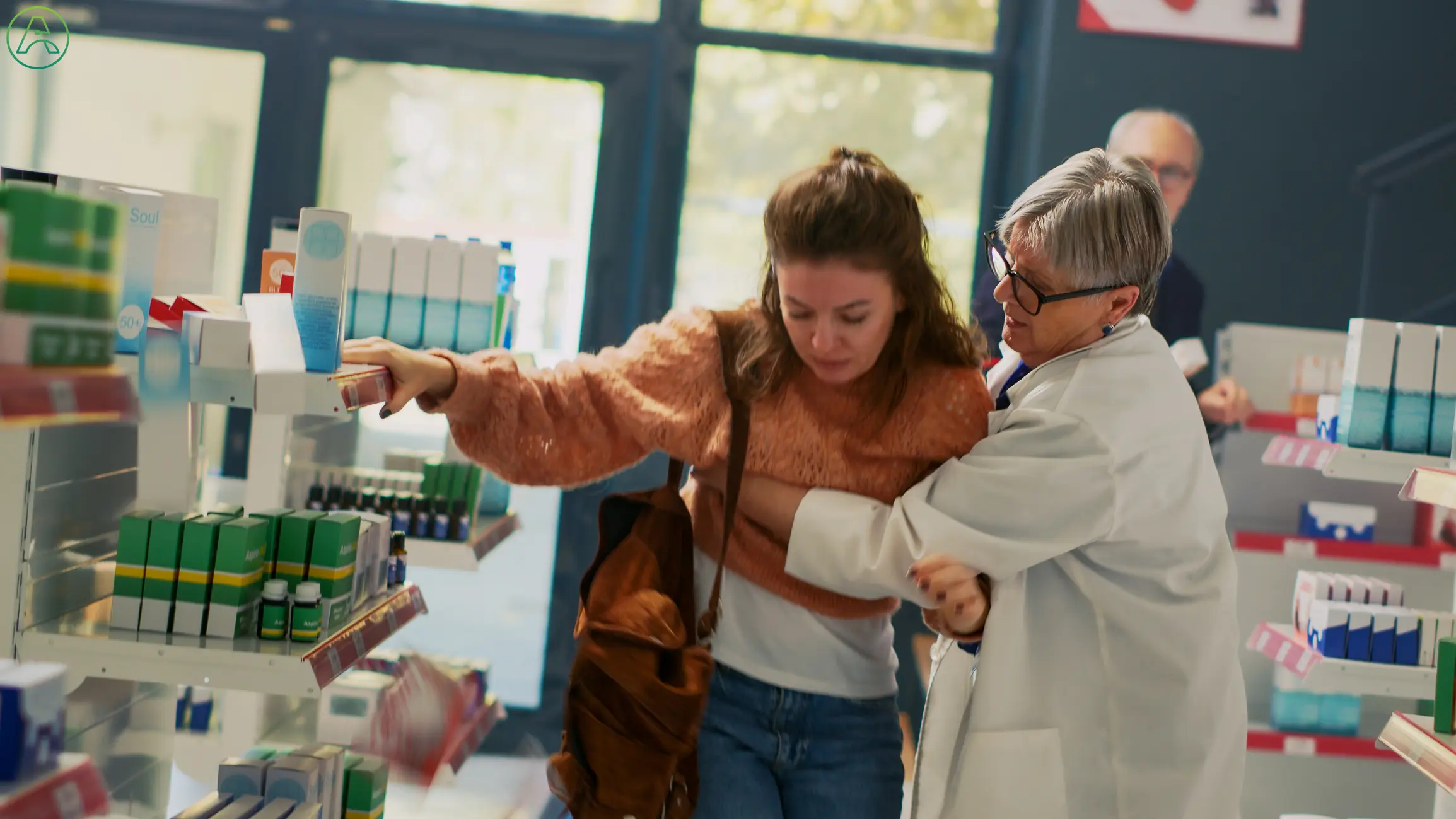 A concerned female pharmacist with short white hair recognizes early stroke symptoms when she holds a young white woman in an orange sweater to keep her from falling.