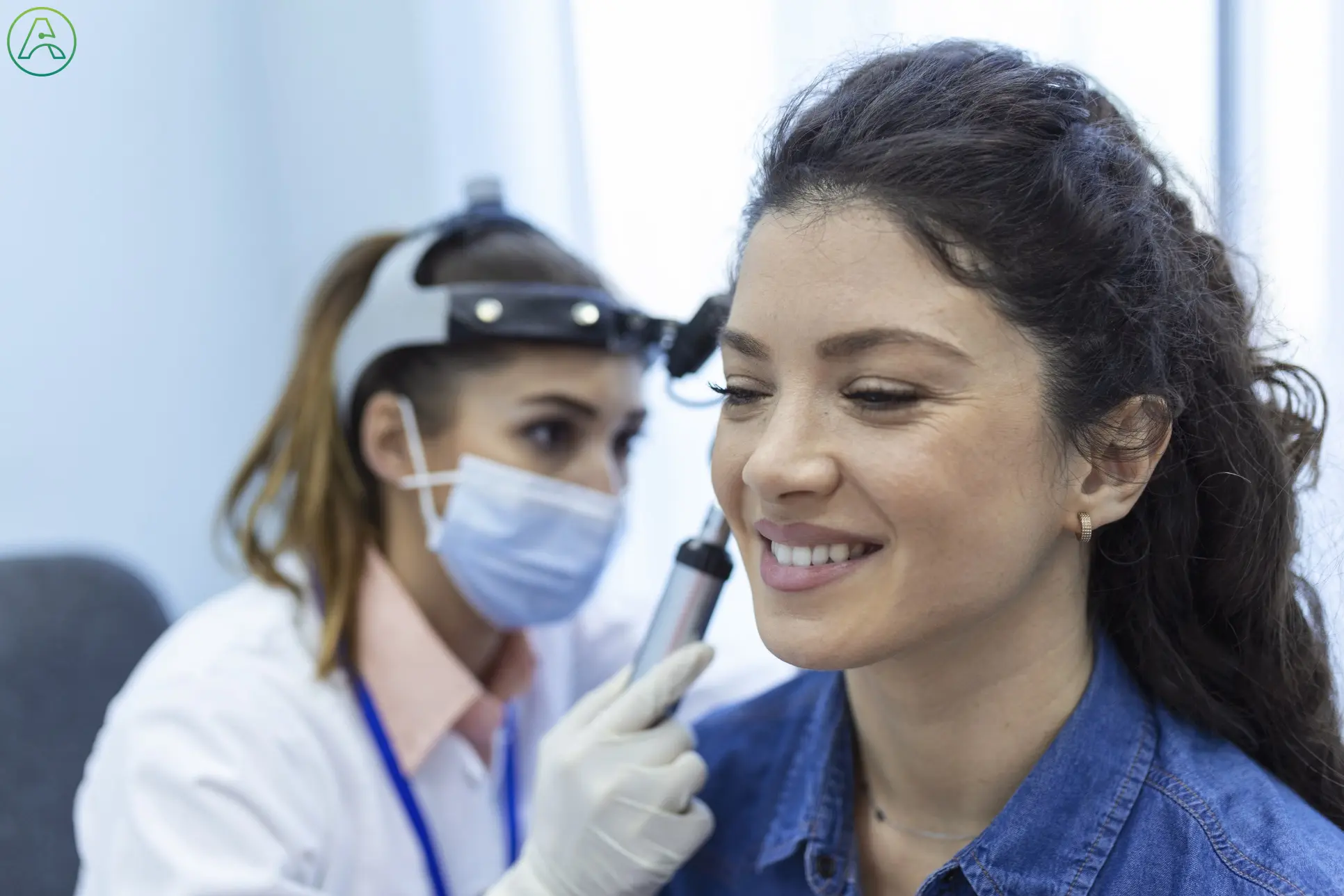 Hearing loss diagnosis - Latina woman sits as a female doctor examines her ear.