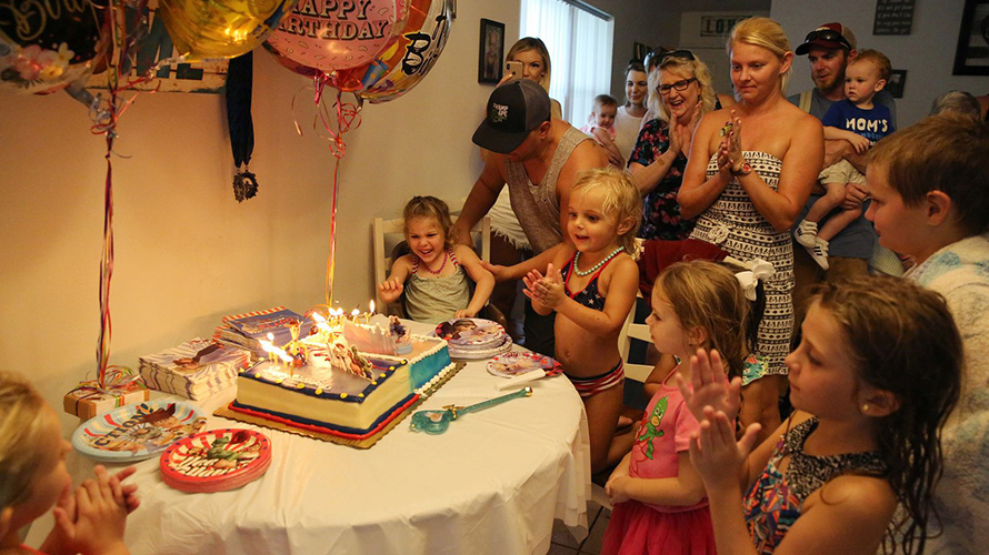 Brooklyn Grant, 7, and her sister Addy Stromquist, 4, prepare to blow out candles as family and friends sing happy birthday to them at their home in Cocoa, Florida, in September 2020. A celebration of Brooklyn’s April birthday was delayed because of the COVID-19 pandemic. Credit:Emily Michot/Miami Herald