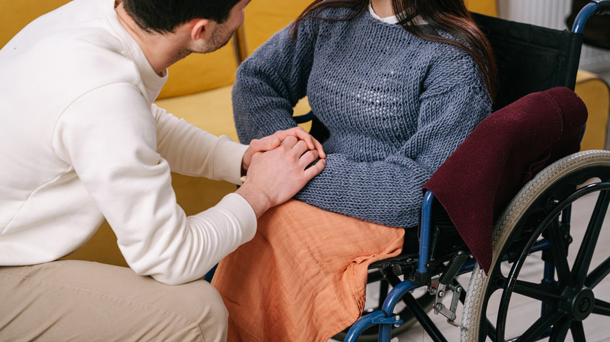 Man kneeling in front of woman in wheelchair