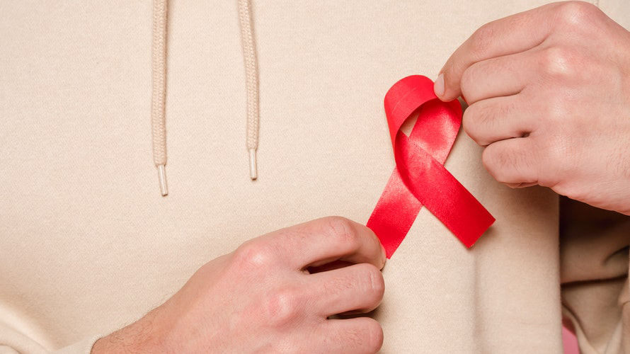 man putting a red AIDS ribbon on his chest