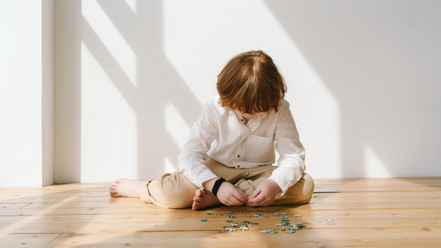 Boy putting puzzle together alone on floor