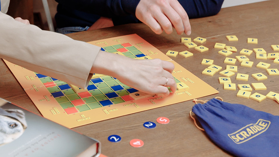 Hands playing Scrabble to improve language skills