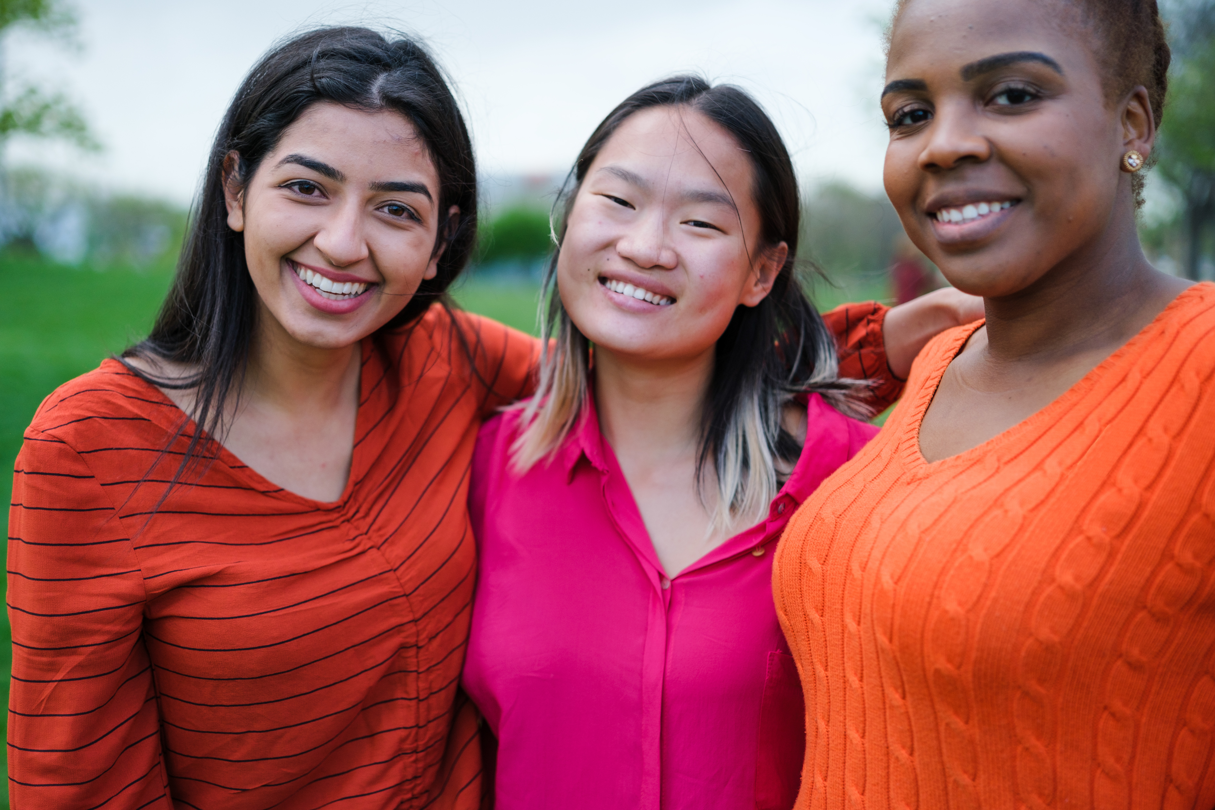 Diverse trio of women in cheerful clothing smile at the camera