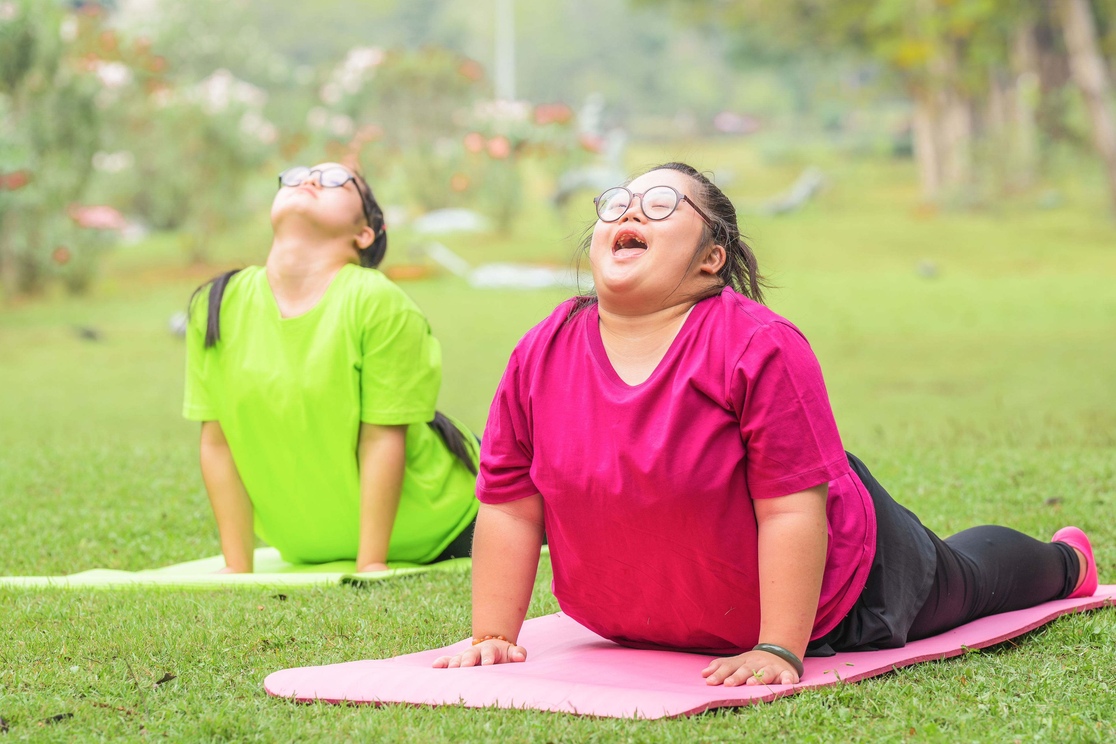 Two young women with Down syndrome practice yoga outdoors